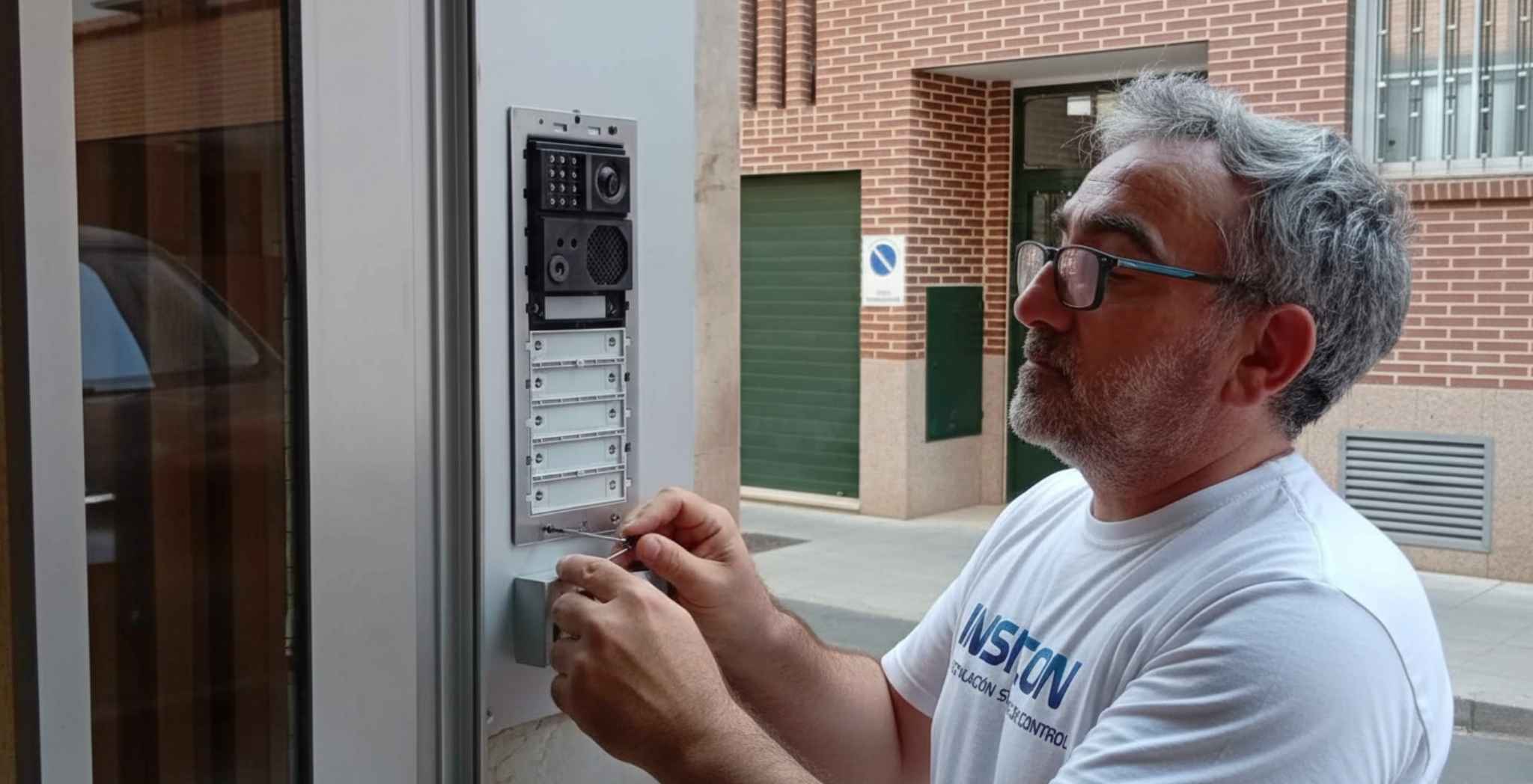 La foto muestra una imagen de un técnico de la empresa INSICON haciendo un mantenimiento sobre un videoportero